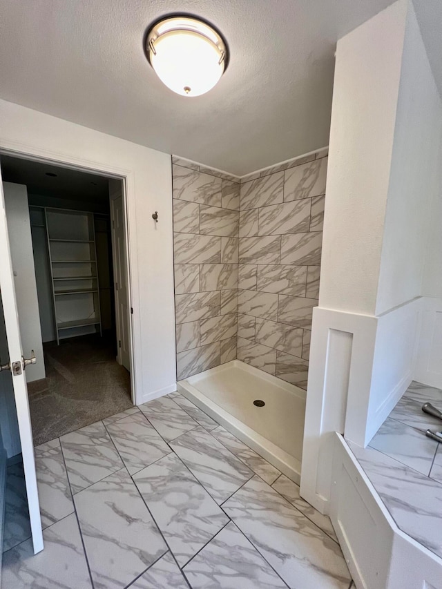 bathroom with a tile shower and a textured ceiling