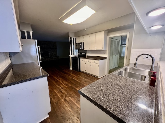 kitchen with a sink, stainless steel appliances, dark wood-type flooring, a fireplace, and white cabinets