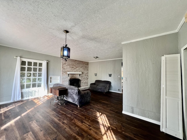 living area featuring hardwood / wood-style floors, a textured ceiling, crown molding, a brick fireplace, and baseboards