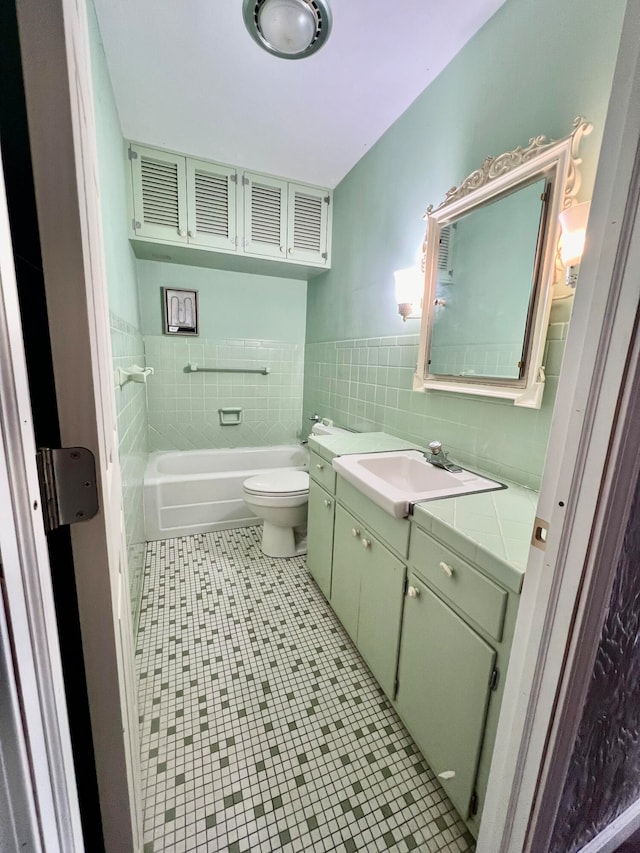 bathroom with tile walls, vanity, a bathtub, and toilet