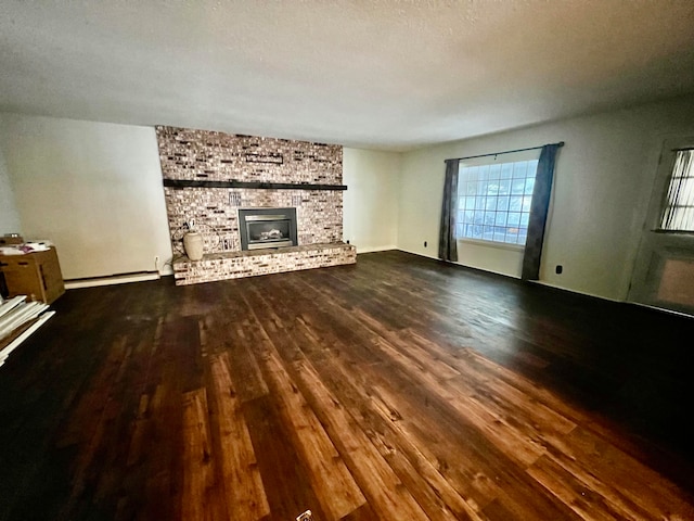 unfurnished living room featuring wood-type flooring, a textured ceiling, baseboard heating, and a fireplace