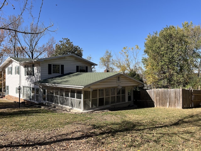 back of property with a sunroom, a chimney, fence, and a lawn