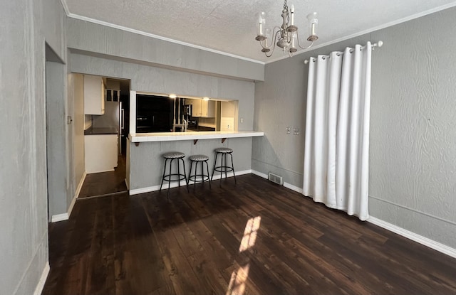dining space featuring ornamental molding, a textured ceiling, visible vents, a chandelier, and dark wood-style floors