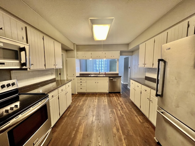 kitchen featuring tasteful backsplash, a textured ceiling, dark wood-type flooring, dark countertops, and appliances with stainless steel finishes