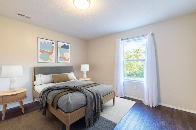 bedroom featuring a textured ceiling and dark hardwood / wood-style floors