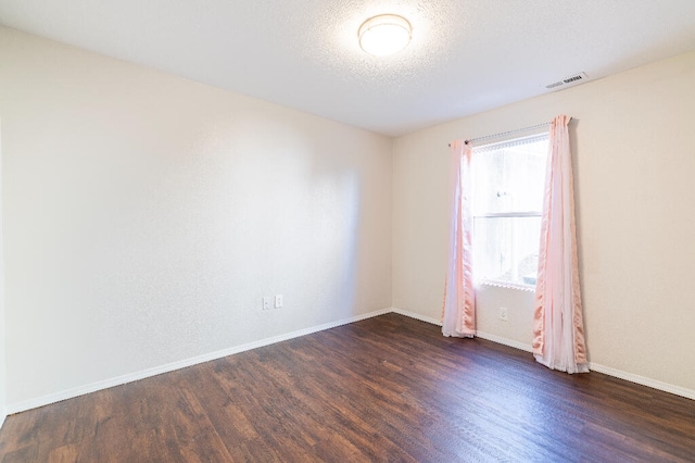 unfurnished room featuring dark wood-type flooring and a textured ceiling