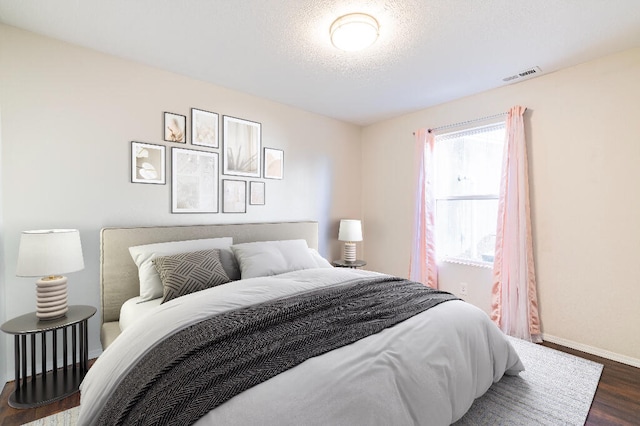 bedroom featuring a textured ceiling and dark wood-type flooring