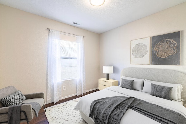 bedroom featuring a textured ceiling and dark hardwood / wood-style floors