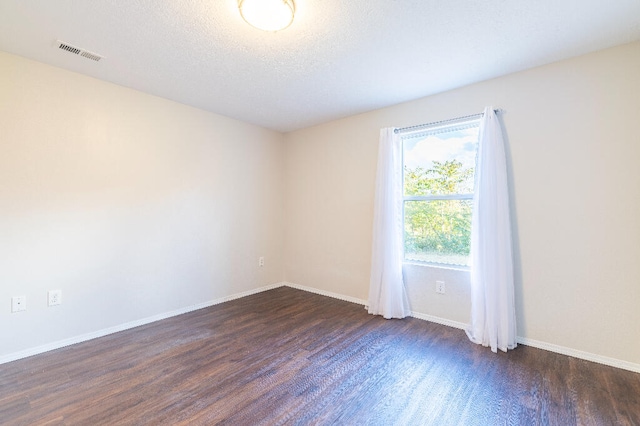 empty room featuring a textured ceiling and dark hardwood / wood-style flooring