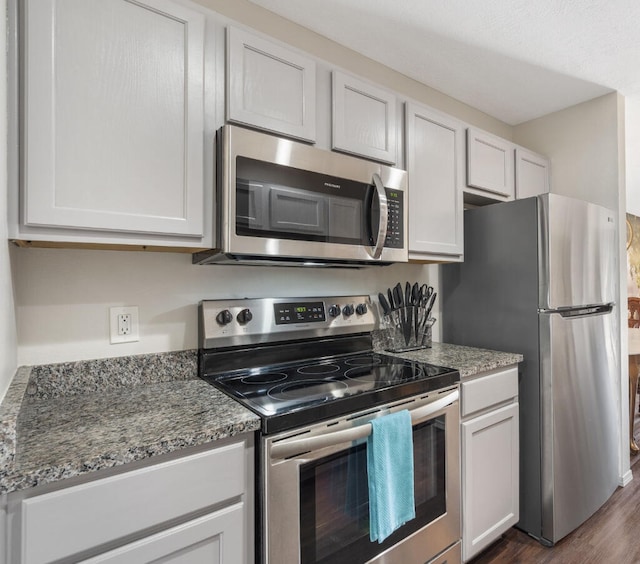 kitchen featuring stone counters, white cabinetry, stainless steel appliances, and dark hardwood / wood-style flooring