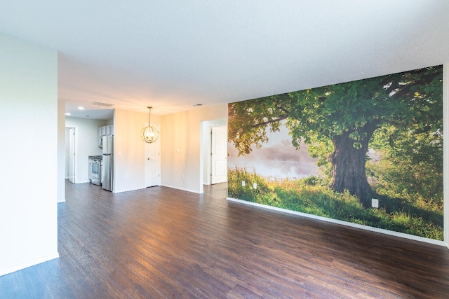 spare room with a notable chandelier and dark hardwood / wood-style floors