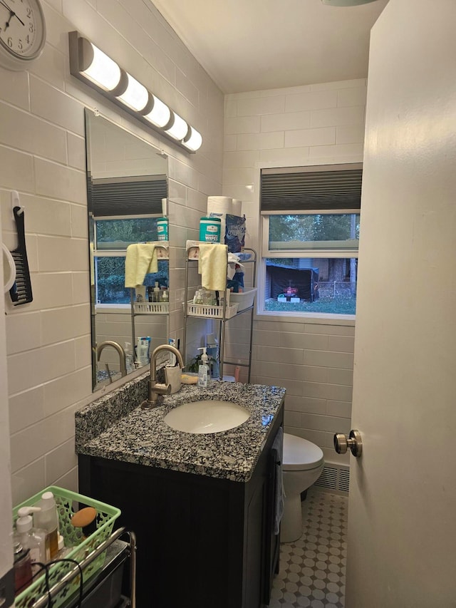 bathroom featuring vanity, toilet, and tile walls