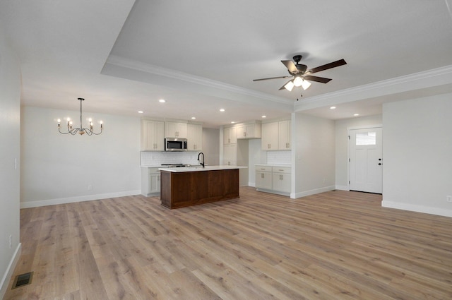 kitchen with a center island with sink, decorative backsplash, light wood-type flooring, ornamental molding, and white cabinetry