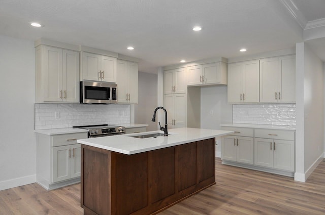 kitchen with sink, white cabinets, light hardwood / wood-style flooring, and appliances with stainless steel finishes