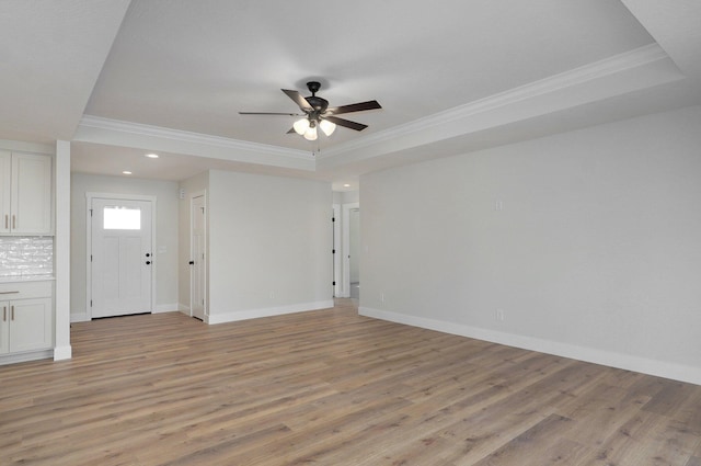 unfurnished room with ceiling fan, a raised ceiling, crown molding, and light hardwood / wood-style flooring