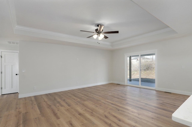 unfurnished room with a raised ceiling, ceiling fan, light hardwood / wood-style flooring, and ornamental molding