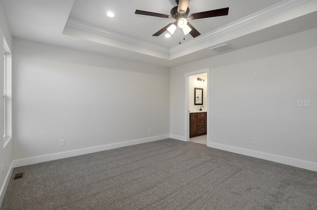 carpeted spare room with a raised ceiling, ceiling fan, and ornamental molding