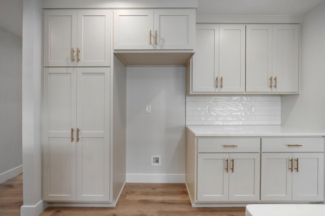 kitchen featuring white cabinets, light wood-type flooring, and backsplash