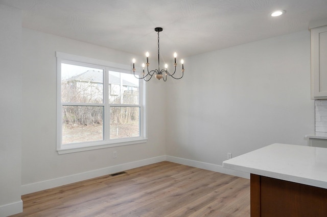 unfurnished dining area with a healthy amount of sunlight, light wood-type flooring, and an inviting chandelier