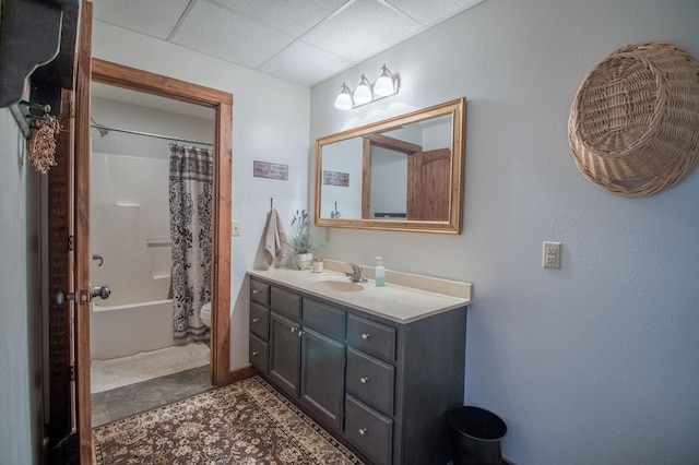 full bathroom featuring vanity, toilet, shower / bathtub combination with curtain, and a drop ceiling