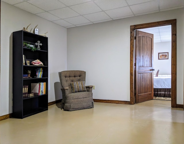 sitting room featuring a paneled ceiling and concrete floors