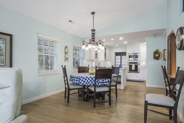 dining room featuring lofted ceiling, hardwood / wood-style floors, a chandelier, and sink