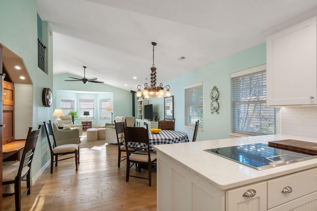 kitchen featuring black electric stovetop, tasteful backsplash, light hardwood / wood-style floors, vaulted ceiling, and white cabinets