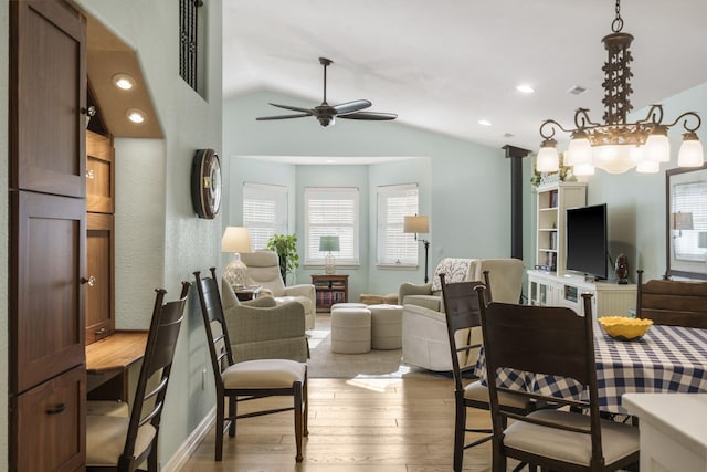 living room with wood-type flooring, ceiling fan with notable chandelier, and vaulted ceiling