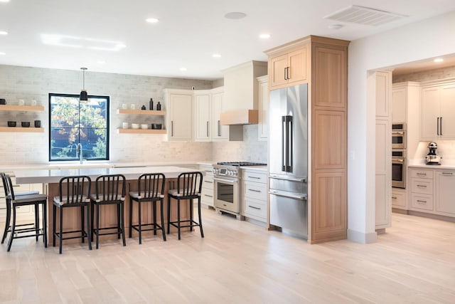 kitchen with open shelves, a breakfast bar area, decorative backsplash, light countertops, and high end appliances