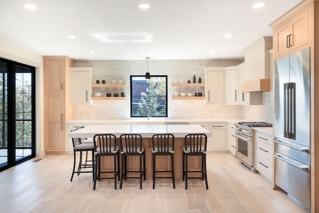 kitchen with high end appliances, a center island, and light wood-type flooring