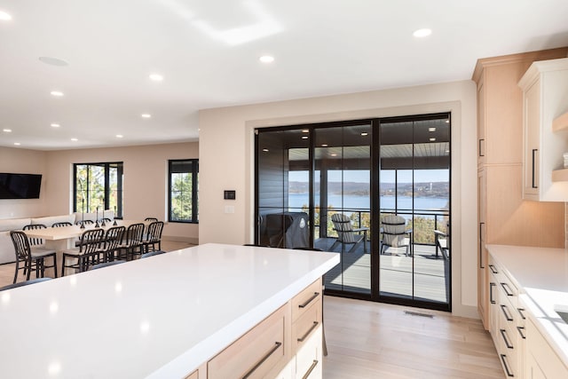 kitchen featuring light brown cabinetry, light hardwood / wood-style flooring, and a water view