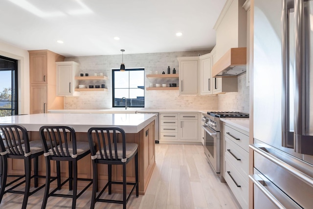 kitchen featuring open shelves, a breakfast bar area, stainless steel appliances, and custom exhaust hood