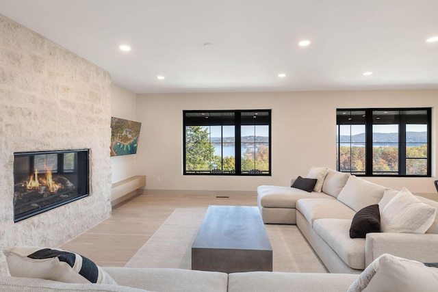 living area with a large fireplace, light wood-style floors, and recessed lighting
