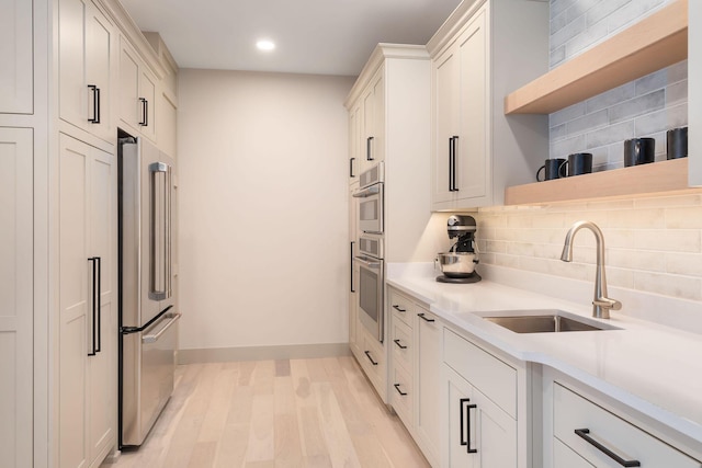 kitchen featuring a sink, open shelves, backsplash, high quality fridge, and light countertops