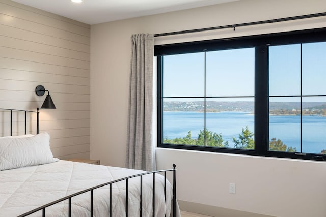 bedroom featuring a water view and wood walls