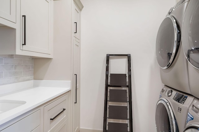 clothes washing area featuring cabinet space and stacked washer / dryer