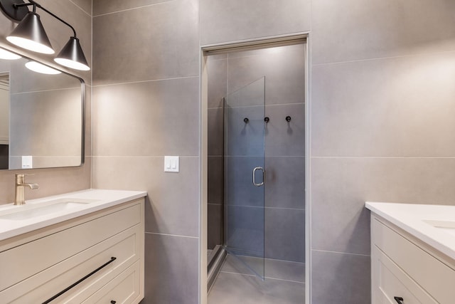 bathroom featuring a shower with door, tile walls, and vanity