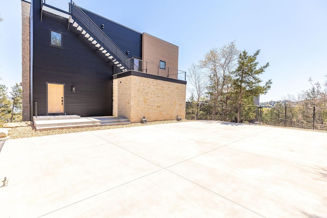 back of property with stone siding, fence, and a balcony