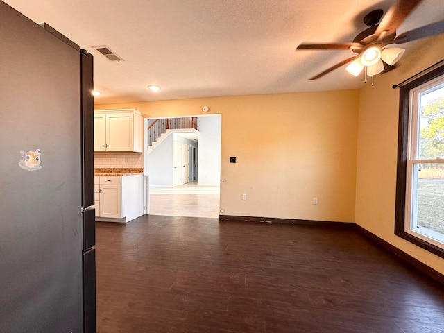 unfurnished living room with ceiling fan, a textured ceiling, and dark hardwood / wood-style flooring