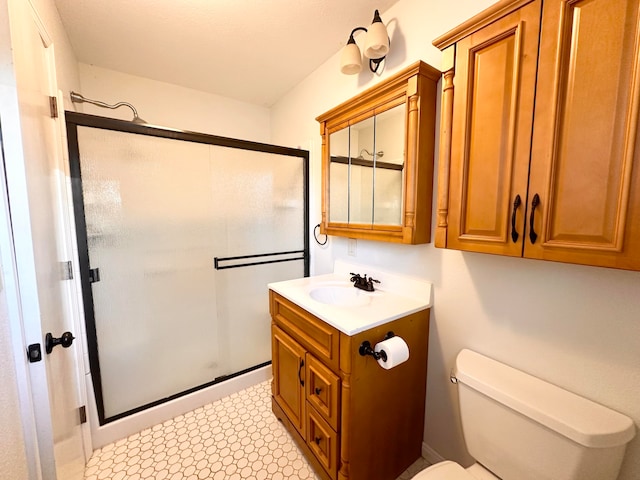 bathroom featuring toilet, a shower with shower door, and vanity