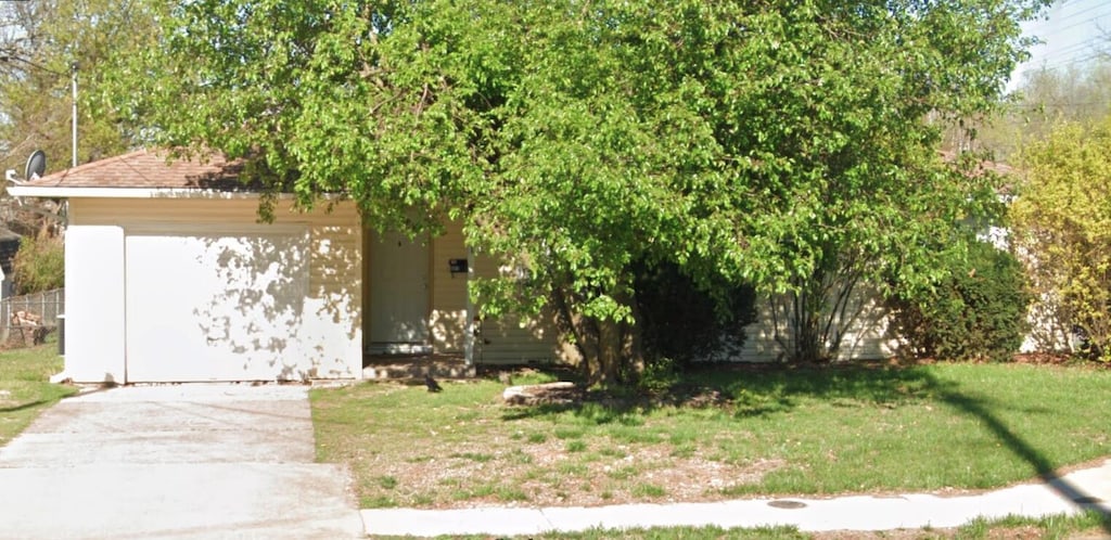 view of property hidden behind natural elements featuring a front lawn