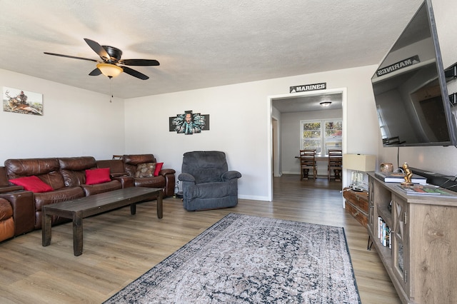 living room featuring a textured ceiling, light wood-type flooring, and ceiling fan