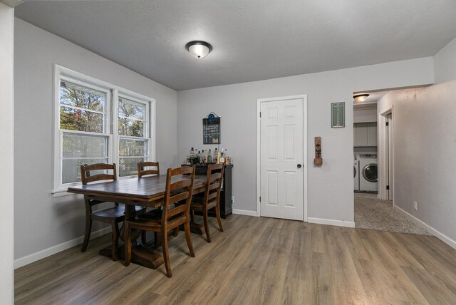 dining space with a textured ceiling, wood-type flooring, and washing machine and clothes dryer