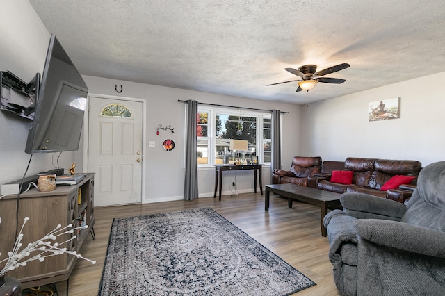 living room with ceiling fan, wood-type flooring, and a textured ceiling