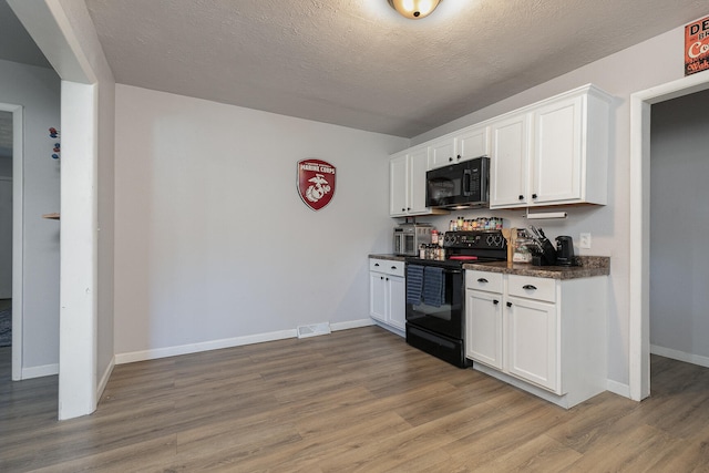 kitchen featuring a textured ceiling, black appliances, light hardwood / wood-style flooring, and white cabinets