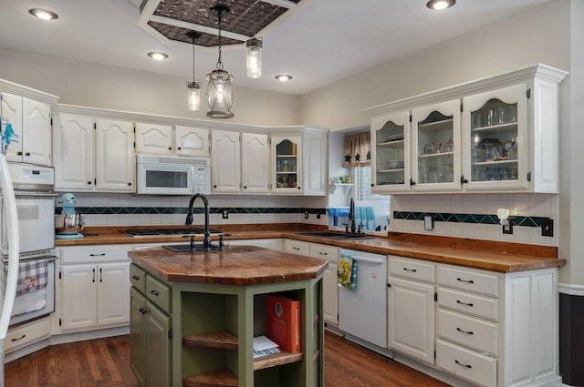 kitchen featuring a center island with sink, pendant lighting, white cabinetry, butcher block countertops, and white appliances