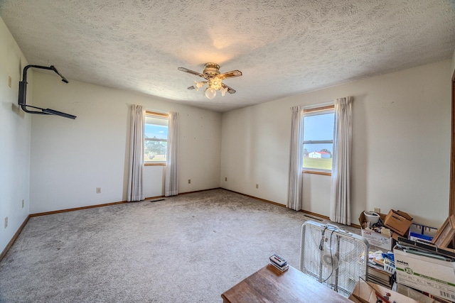 carpeted spare room with a textured ceiling and ceiling fan