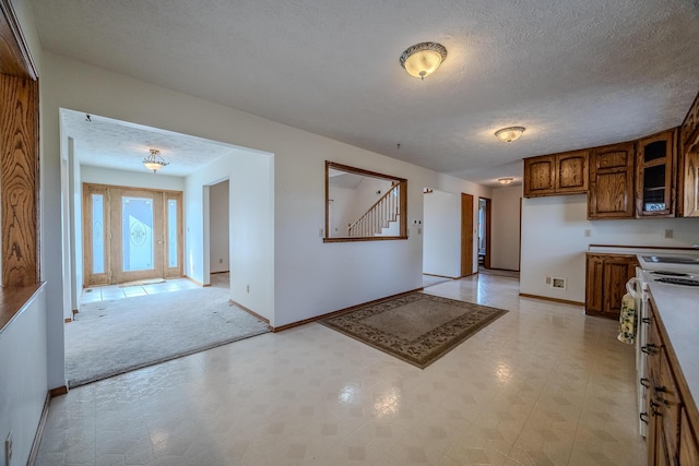 kitchen featuring white electric range, a textured ceiling, baseboards, and glass insert cabinets