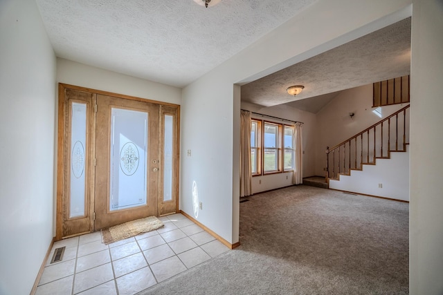 foyer featuring stairs, a textured ceiling, and baseboards