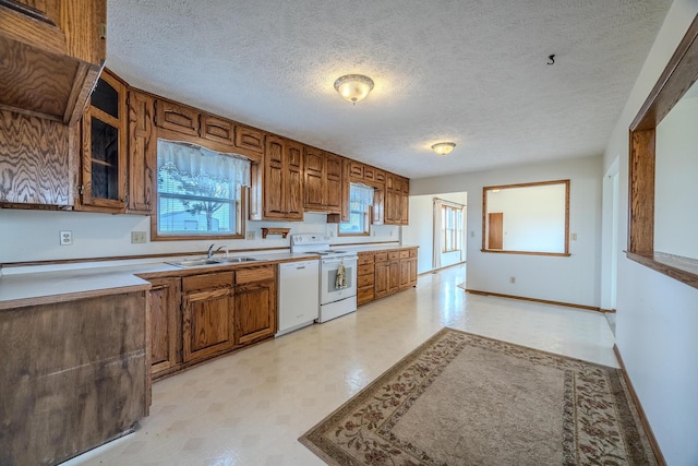 kitchen featuring a sink, brown cabinets, white appliances, and light floors